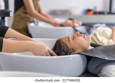 Caucasian young woman get hair washed by hairdresser stylist in salon. Beautiful customer girl lying down on salon washing bed feeling relax and happy enjoy massaging her head at beauty barber shop. - Powered by Shutterstock