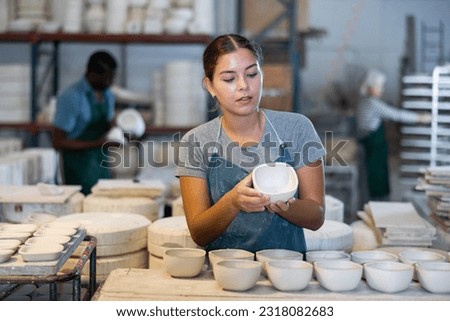 Caucasian young woman potter evaluating quality of new crafted ceramic bowls in workshop. 商業照片 © 