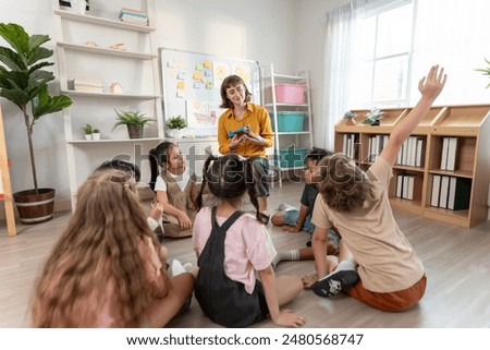 Caucasian young woman teacher teaching student in classroom at school. Attractive beautiful female instructor master explain and educate children with fun activity at preschool nursery kindergarten.