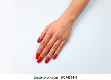 Caucasian young woman's hand with red nails on light blue table. Top view, copy space.  