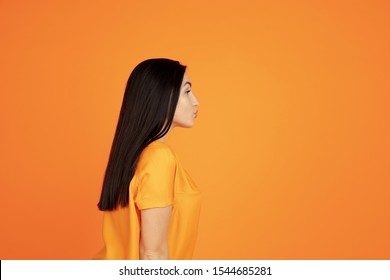 Caucasian young woman's portrait on orange studio background. Beautiful female brunette model in shirt. Concept of human emotions, facial expression, sales, ad. Copyspace. Sending kisses.