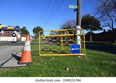 Caulfield South, Victoria, Australia - June 28 2021: A damaged Telstra communication pillar, next to Telstra cable pits access and a traffic cone, still awaiting maintenance