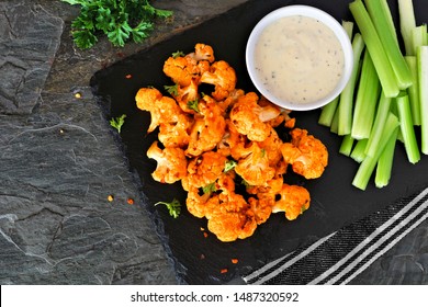 Cauliflower Buffalo Wings With Celery And Ranch Dip. Top View With A Dark Slate Background. Healthy Eating, Plant Based Meat Substitute Concept.