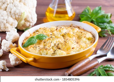 Cauliflower casserole with cheese and milk sauce in a baking dish on wooden table