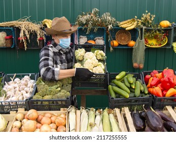 Cauliflower At The Farmers' Market. A Male Salesman Places A Box Of Cauliflower On The Counter.
The Seller In A Protective Medical Mask.