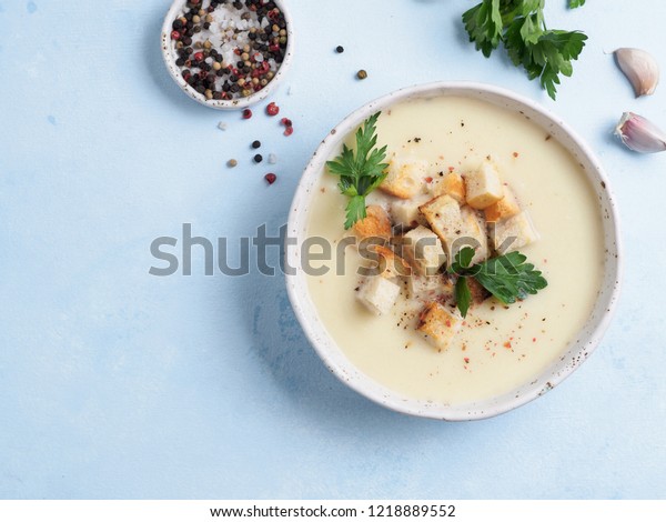 cauliflower potato soup puree on blue tabletop,\
Creamy cauliflower soup with toasted bread croutons. Vegetarian\
healthy food concept. Ideas and recipes for winter meal. Top view\
or flat lay.Copy\
space