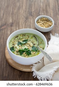 Cauliflower Puree Soup With Parsley And Pine Nuts In A White Bowl On A Wooden Table. Delicious Diet Food