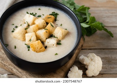 Cauliflower soup in a bowl on wooden table - Shutterstock ID 2307548767