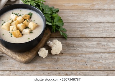 Cauliflower soup in a bowl on wooden table. Copy space - Shutterstock ID 2307548787