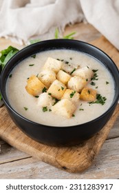 Cauliflower soup in a bowl on wooden table - Shutterstock ID 2311283917