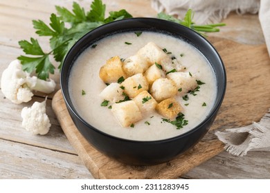 Cauliflower soup in a bowl on wooden table - Shutterstock ID 2311283945