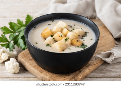 Cauliflower soup in a bowl on wooden table - Shutterstock ID 2311283949