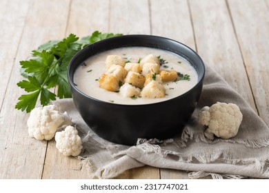 Cauliflower soup in a bowl on wooden table - Shutterstock ID 2317747021