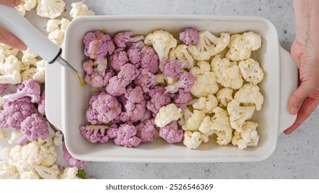 Cauliflower, white and purple, in baking pan with olive oil, salt and garlic seasoning, ready to be baked, woman hands, flat lay - Powered by Shutterstock