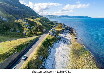 Causeway Costal Route With A Car, A.k.a. Antrim Coastal Road On Eastern Coast Of Northern Ireland, UK. Aerial View