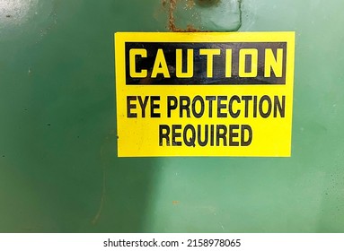 A caution eye protection yellow-colored sign with green background - Shutterstock ID 2158978065
