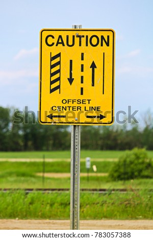 A caution offset center line road sign.