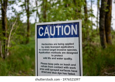 Caution Sign Informing Visitors Of Herbicides Being Applied To Control Target Invasive Species In A Nature Park.