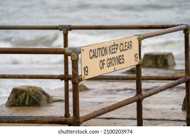 Caution Sign On Beach Groin