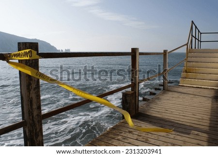 caution tape blowing in the wind with the sea in the background