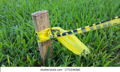 Caution Tape Tied Around Small Stake In Grass