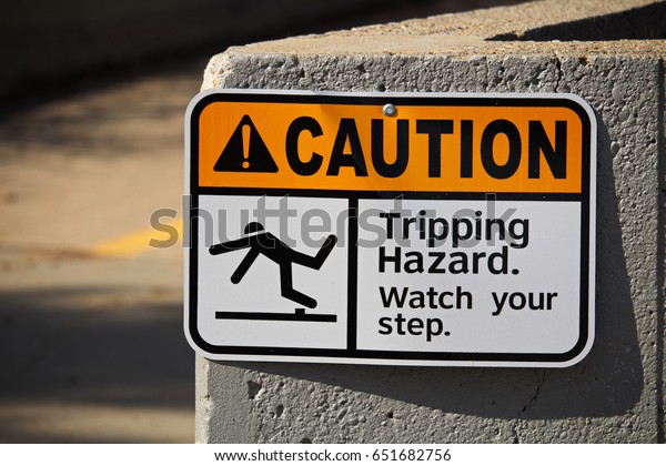 Caution tripping hazard\
sign on a wall.