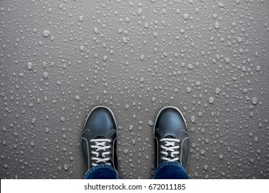 Caution, wet floor. Black shoes standing on wet floor. Slippery and dangerous. Need careful walk.