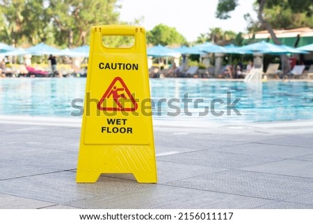 caution wet floor warning sign near swimming pool in hotel.