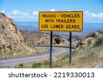 A cautionary sign for trucks and vehicles with trailers to use lower gears while driving down hill