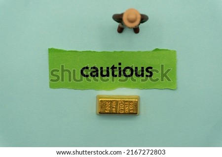 cautious.The word is written on a slip of paper,on colored background. professional terms of finance, business words, economic phrases. concept of economy.
