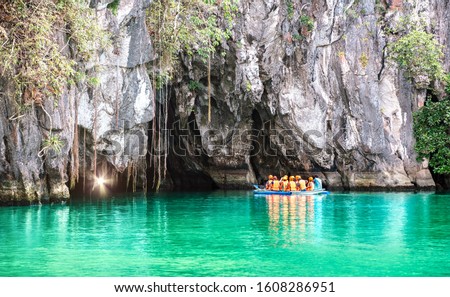 Cave entrance of Puerto Princesa subterranean underground river with longtail boat - Wanderlust travel concept at Palawan exclusive Philippine destination - Vivid filter with bulb torch light sunflare