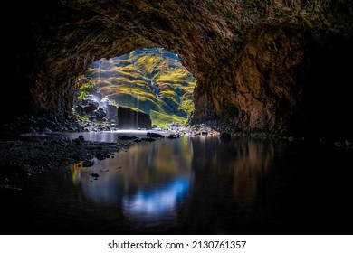 A cave in the mountain filled with water. Water in mountain cave. Mountain cave water flow. Water in cave - Shutterstock ID 2130761357