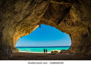 Cave on the beach of Cala Luna from inside to the sea with two people
