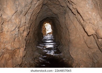 a cave in rocky mountain with river on the floor - Powered by Shutterstock