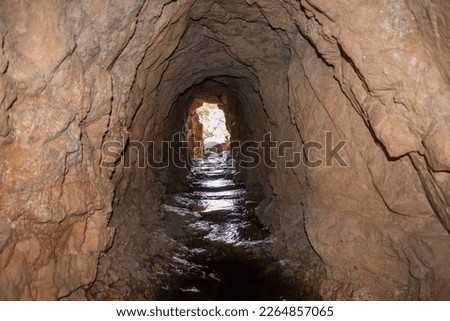 a cave in rocky mountain with river on the floor