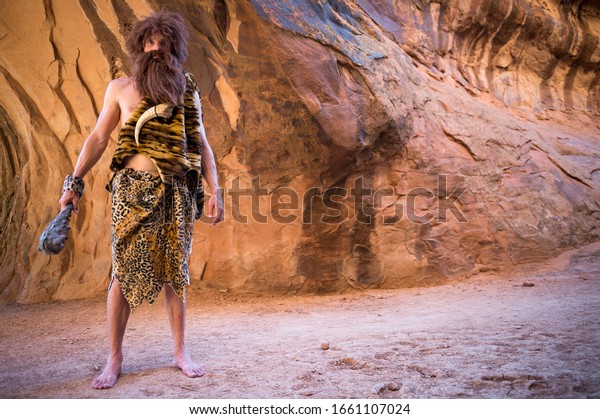 Caveman standing outdoors holding his club in an empty\
cave 