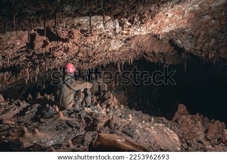 a caver sitting and looking at the cave formations surounding him