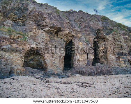 Caves in eroded mudstone cliffs at Runswick Bay in North Yorkshire, UK - part of the Whitby Mudstone Formation - sedimentary bedrock formed around 174 to 183 million years ago in the Jurassic Period
