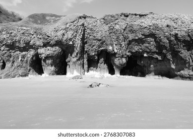 Caves in the rugged limestone cliffs at the sandy beach in Pendine, Carmarthenshire, Wales, UK.