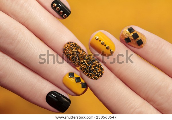 	  Caviar manicure\
in yellow black nails with black and gold rhinestones on a yellow\
background.
