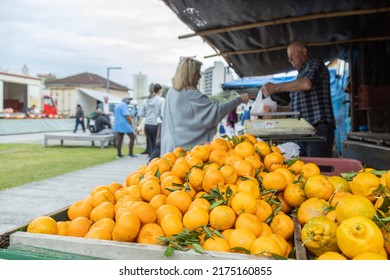 Caxias do Sul, Rio Grande do Sul, Brazil - Jun 28th, 2022: Tangerines at Market Square (Praca das Feiras). Defocused people on background buying fresh food, vegetables and fruits Foto Editorial Stock