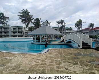 Cayo Coco, Cuba, 16 May 2021: The Hotel Employee Cleans The Pool Area Before The Arrival Of Vacationers. Man Stands Knee-deep In The Pool Water And Cleans The Bottom With A Mop.