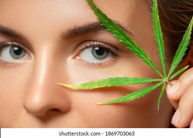 CBD Cosmetics Concept. Beautiful Woman With A Cannabis Leaf On Gray Background