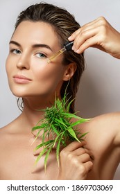 CBD cosmetics concept. Beautiful woman with a cannabis leaf on gray background