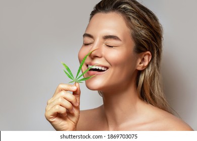 CBD cosmetics concept. Beautiful woman with a cannabis leaf on gray background