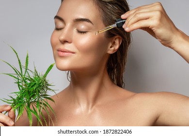 CBD Cosmetics Concept. Beautiful Woman With A Cannabis Leaf On Gray Background