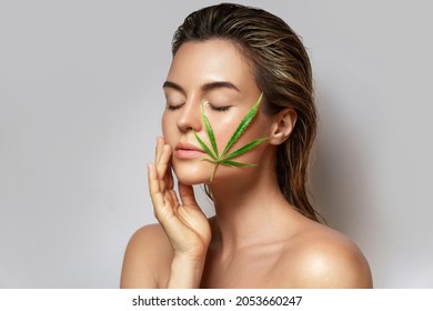 CBD Cosmetics Concept. Beautiful Woman With A Cannabis Leaf On Gray Background