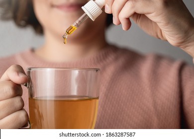 Cbd Hemp Oil - Woman Taking Cannabis Oil In Tea Cup - Focus On Drop