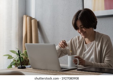 Cbd hemp - Woman taking cannabidiol oil in tea cup while working at home office - Focus on dropper