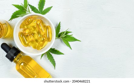 Cbd Oil, Capsules And Fresh Hemp Leaves On Light Gray Table